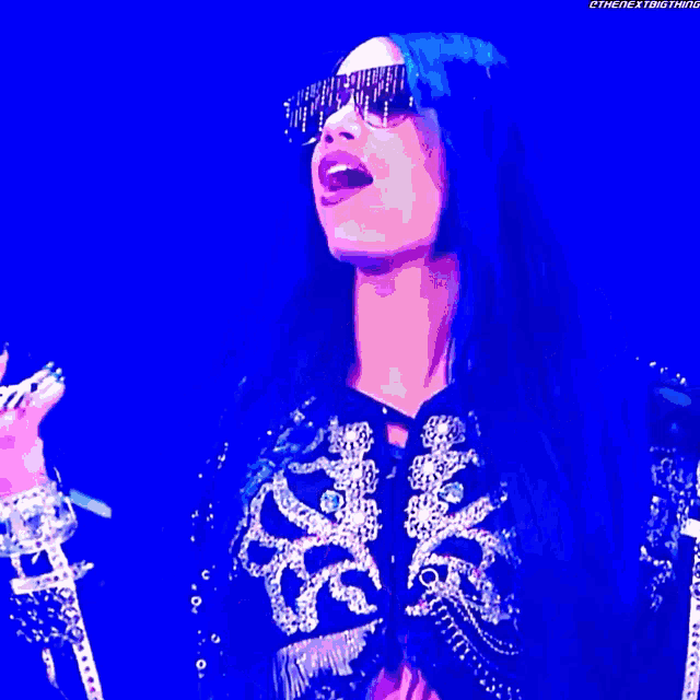 a woman wearing sunglasses stands in front of a blue background that says " thenextthing "