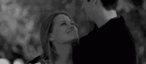 a black and white photo of a man and a woman hugging and kissing .