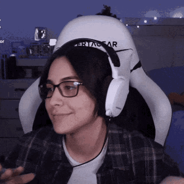 a woman wearing glasses and headphones is sitting in a white chair that says certogear