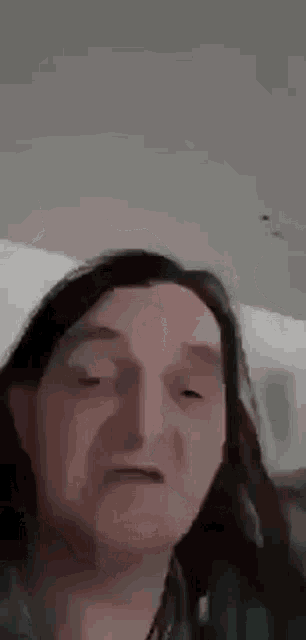 a man with long hair is making a funny face while looking at the camera .
