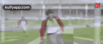 a man in a red jacket and white pants is running on a field .