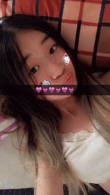 a girl with a hello kitty sticker on her face is laying on a bed