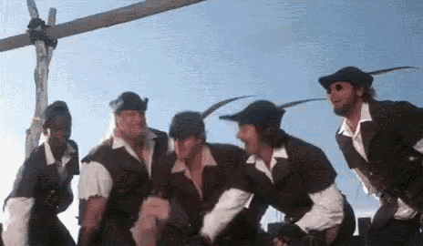 a group of men in medieval costumes are standing next to each other in front of a wooden cross .