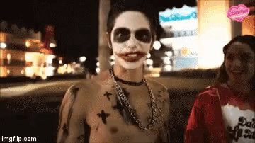 a man in a joker costume is standing next to a woman wearing a shirt that says ' sad girl ' on it