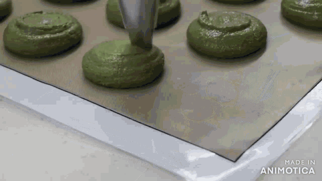 a bunch of green cookies are being poured on a baking sheet made in animotica