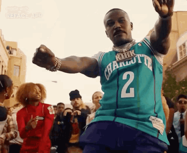 a man is wearing a charlotte hornets jersey and dancing in front of a crowd .