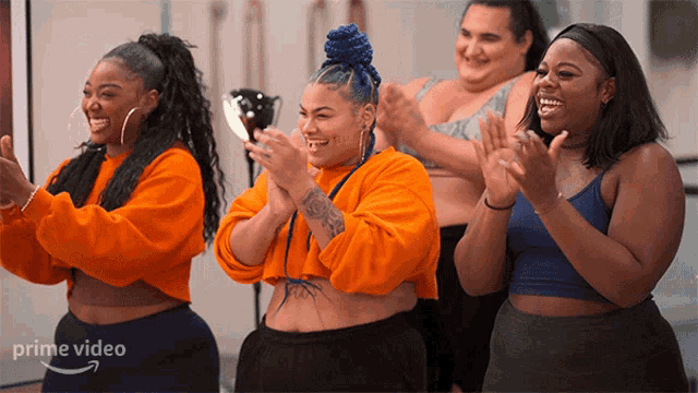 a group of women are clapping in front of a sign that says " prime video "