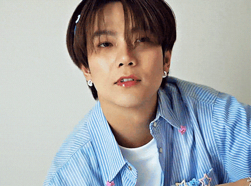 a young man wearing a blue striped shirt and earrings