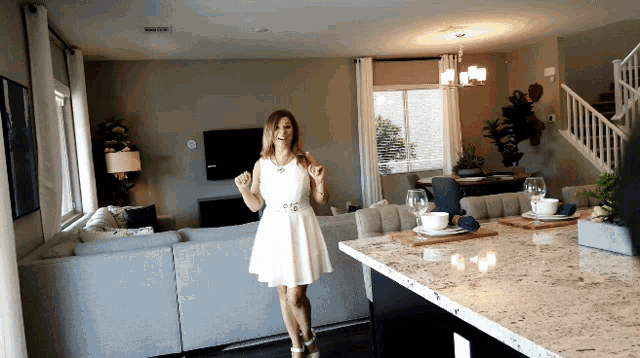 a woman in a white dress stands in front of a living room
