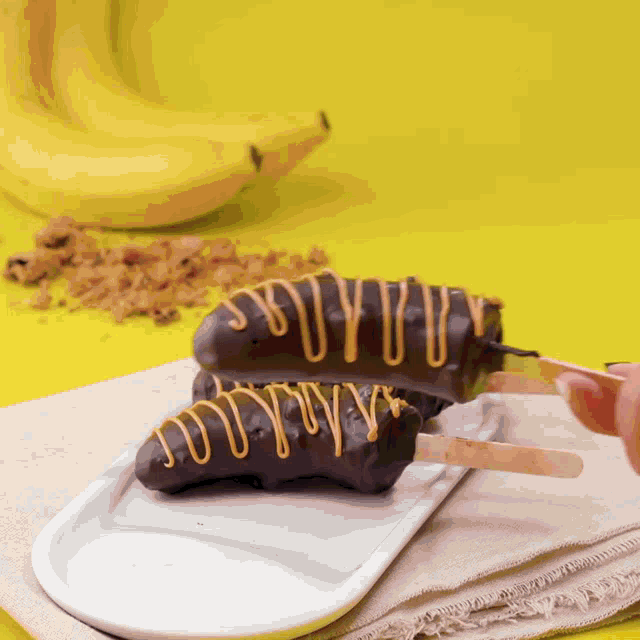 two chocolate covered bananas on a white plate