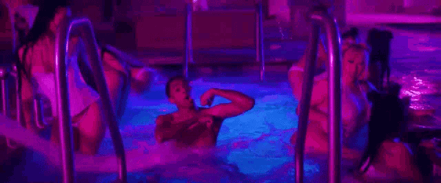 a group of people are swimming in a swimming pool at night .
