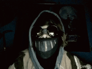 a person wearing a gas mask and a hooded jacket is standing in the dark .