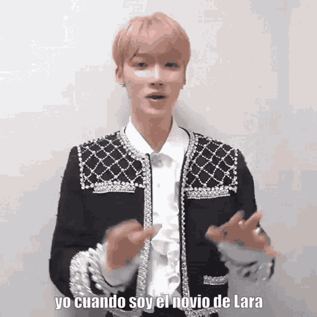 a man with pink hair is wearing a black jacket and a white shirt .