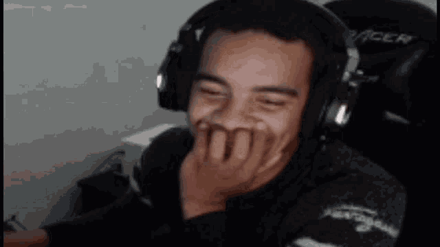 a man wearing headphones is covering his mouth with his hands
