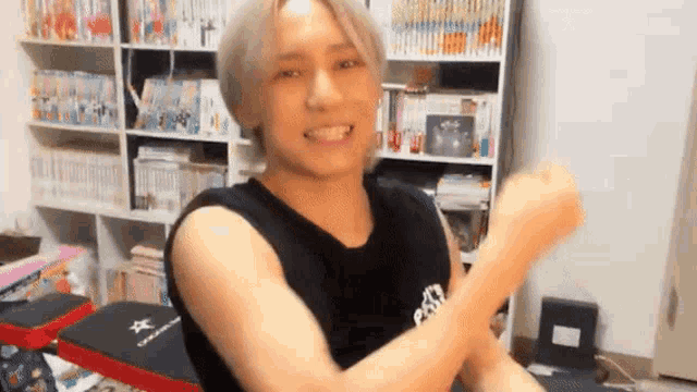 a man in a black tank top is flexing his muscles in a room .