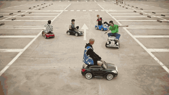 a group of people are playing with toy cars in a parking lot with an arrow pointing to the right