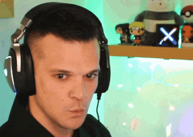 a man wearing headphones stands in front of a shelf with funko pop figures