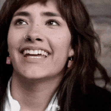 a close up of a woman 's face with a nose ring smiling .