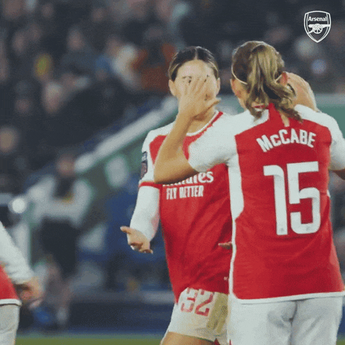 a soccer player with the number 15 on her back is hugging another player