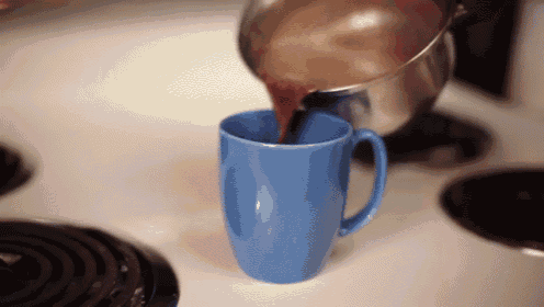 a blue cup of coffee is being poured from a pot