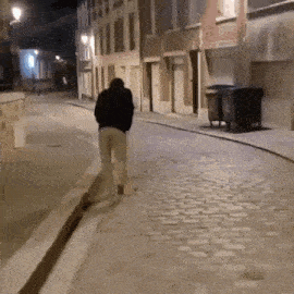 a man is walking down a cobblestone street .