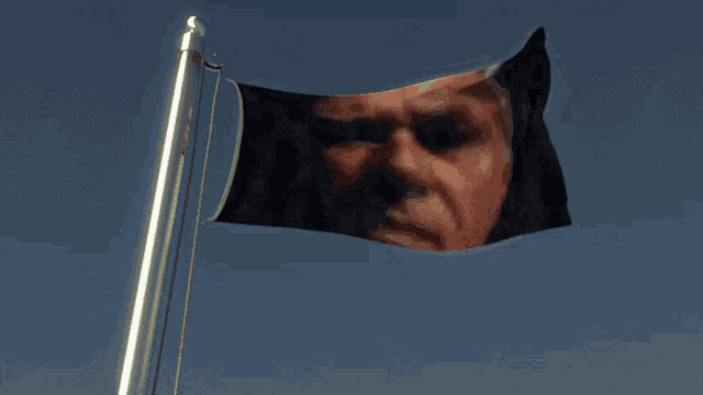 a flag with a man 's face on it is waving in the wind