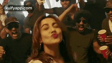 a woman is blowing a kiss at a crowd of people .