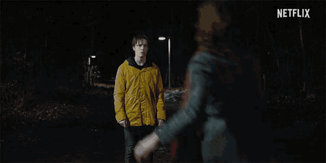 a man in a yellow jacket is standing next to a woman in a blue dress with a netflix logo in the background