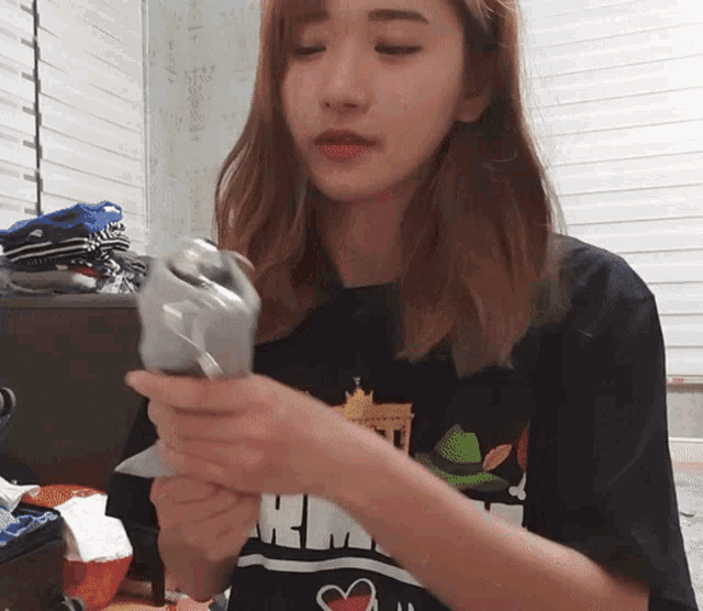 a woman wearing a shirt that says hm is holding something in her hands