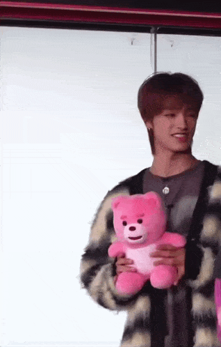 a man is holding a pink teddy bear in his hands .