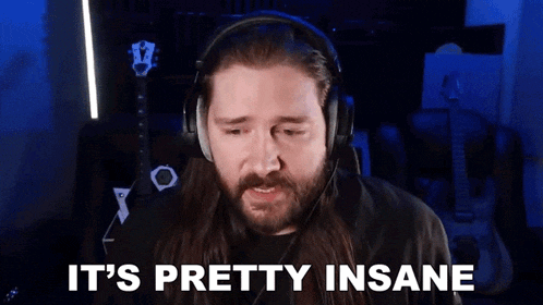 a man with long hair and a beard is wearing headphones and saying `` it 's pretty insane ''