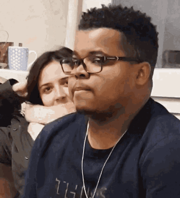 a man wearing glasses is sitting next to a woman wearing headphones