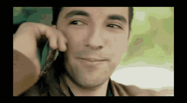 a man is smiling while talking on his cell phone