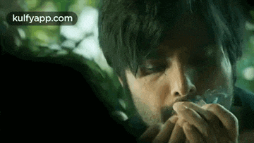 a close up of a man smoking a cigarette in a dark room .