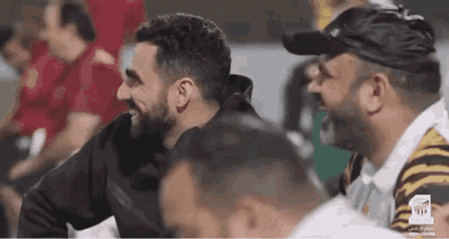 a group of men are sitting in a stadium laughing and talking .