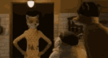 a cat with a fox head is standing in front of a mirror and talking to another cat .