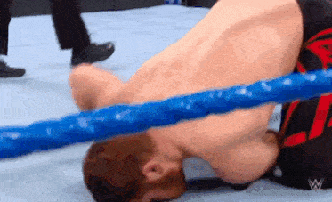 a man is laying on the ground in a wrestling ring with his head in the ring .