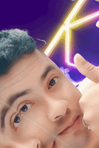 a close up of a man 's face with a neon sign behind him