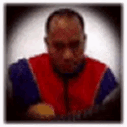 a blurry picture of a man wearing a red vest and a blue shirt .