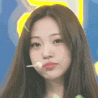 a close up of a woman with long hair holding a lollipop in her mouth .