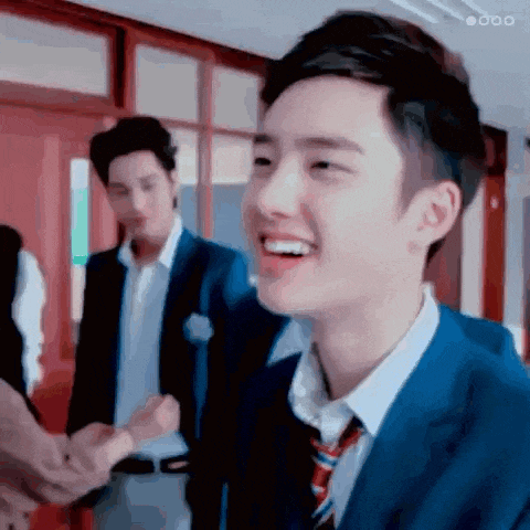 a young man in a suit and tie is shaking hands with another man in a classroom .