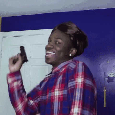 a man in a plaid shirt is holding a gun .