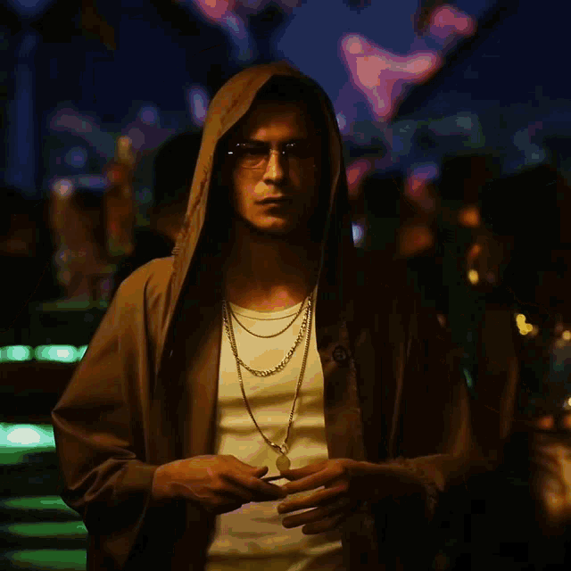 a man is wearing a hooded jacket and a necklace