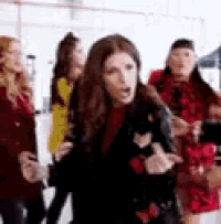 a group of women are standing next to each other in a room and one of them is making a funny face .