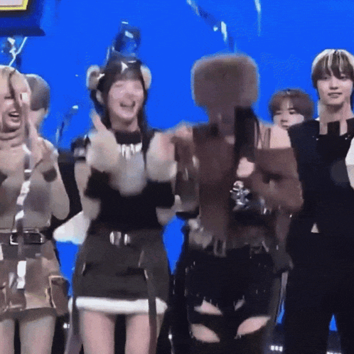 a group of people are standing in front of a blue background applauding