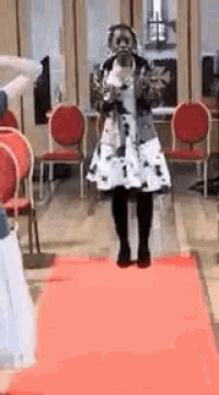 a woman in a white dress is standing on a red carpet .