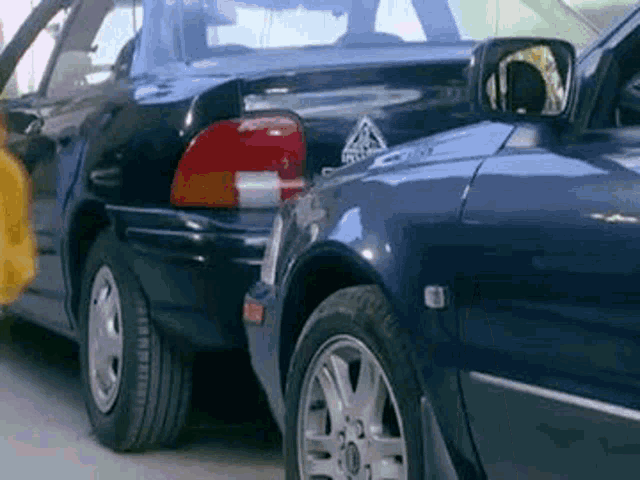 a blue car is parked next to a black car in a parking lot .