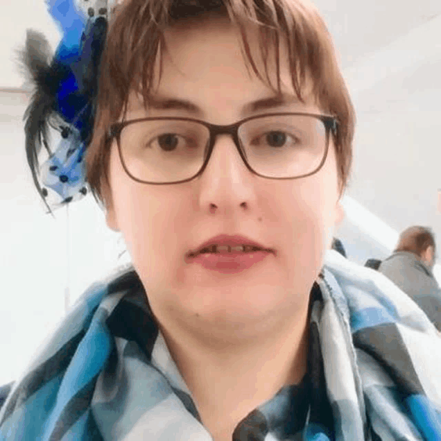 a woman wearing glasses and a blue and black scarf is looking at the camera .
