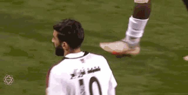 a soccer player wearing a white shirt with the number 10 on it is standing on a soccer field .