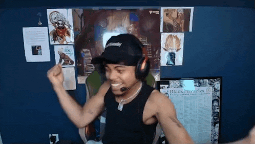 a man wearing headphones and a hat is standing in front of a wall with posters on it .